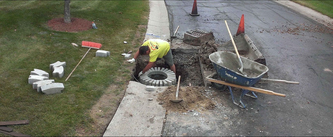 Central Seal Coat employee repairing a concrete catch basin